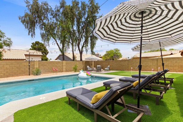 A swimming pool with lounge chairs and a tiki float. - Putting Green! Desert Group Getaway in Chandler (Chandler)