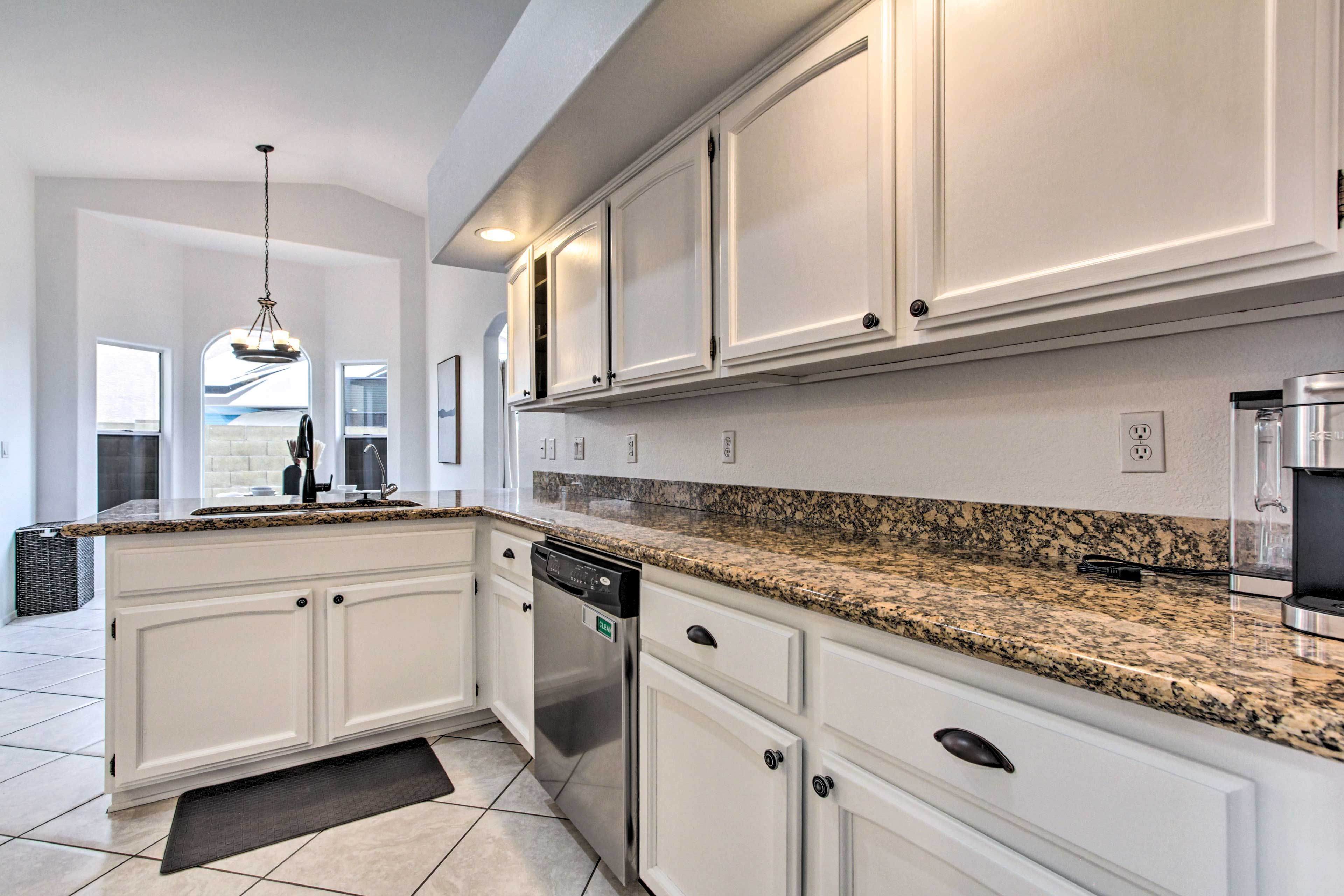 A modern kitchen with white cabinetry, granite countertops, and stainless steel appliances.