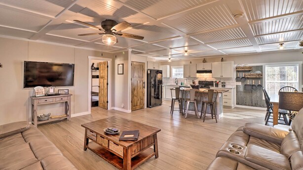 A spacious living area with a wooden coffee table, leather sofa, and a ceiling fan.