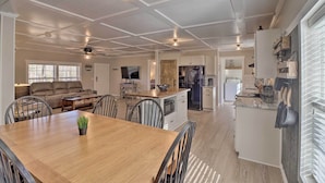 A spacious kitchen with a central island, white cabinetry, and a dining area with a wooden table and chairs.