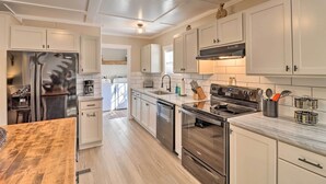 A modern kitchen with white cabinetry, stainless steel appliances, and a wooden dining table.