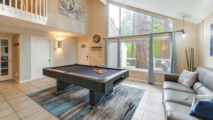 A pool table in a well-lit room with a large window, a sofa, and a staircase. - Expansive Flagstaff Family Retreat w/ Media Room! (Flagstaff)