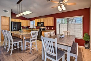 A modern kitchen with wooden cabinets, a central island, and a dining area with white chairs.