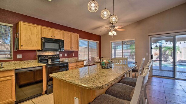 A kitchen with wooden cabinets, a granite countertop, a built-in oven, a microwave, and a dishwasher. There is a seating area with a bench and a table. - Outdoor Kitchen, Heated Pool: Gilbert Retreat! (Gilbert)
