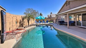 A clear swimming pool with a basketball hoop, blue chairs, and a covered seating area. - Outdoor Kitchen, Heated Pool: Gilbert Retreat! (Gilbert)