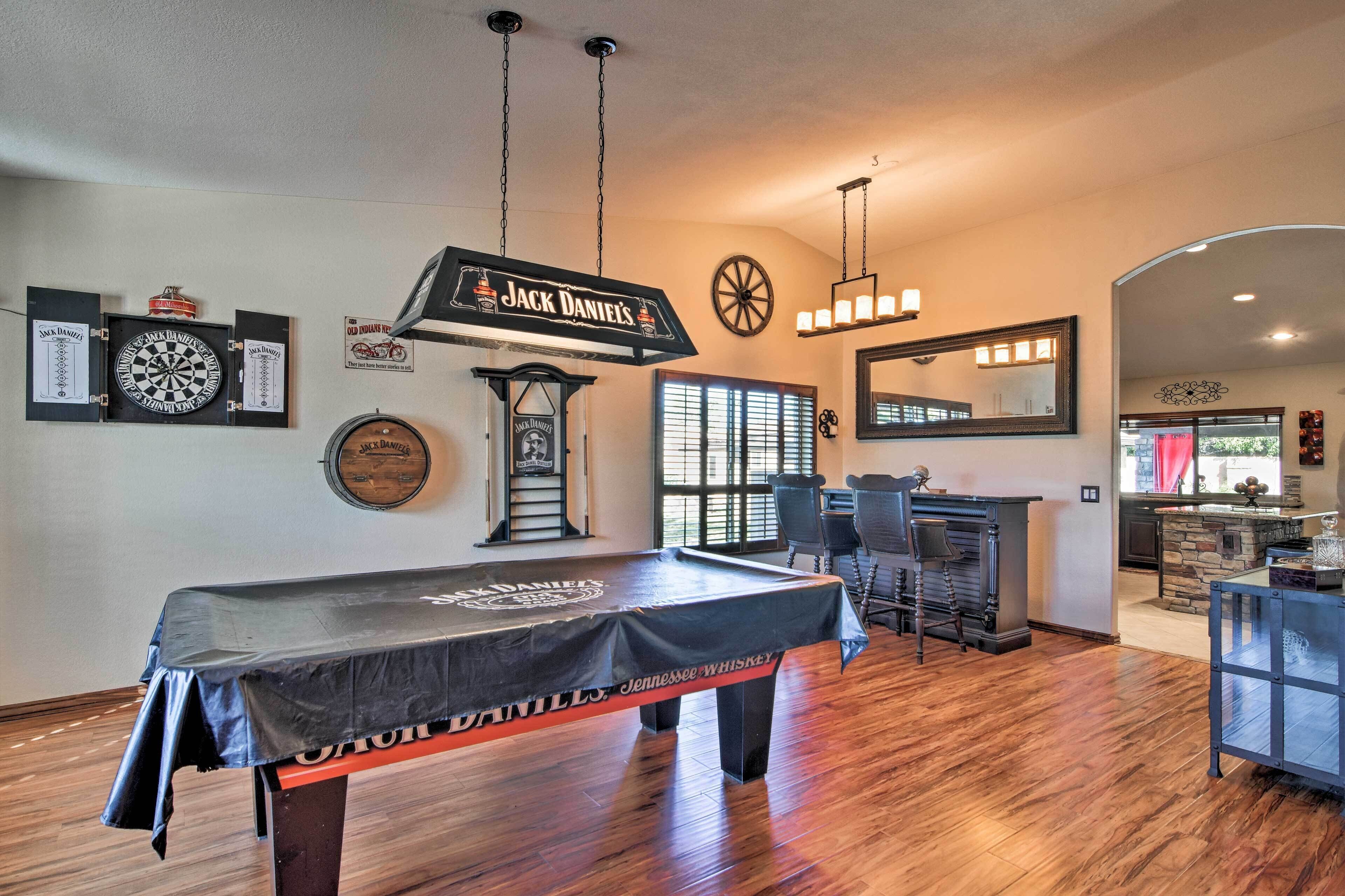 A billiards room with a pool table, dartboards, and a clock.