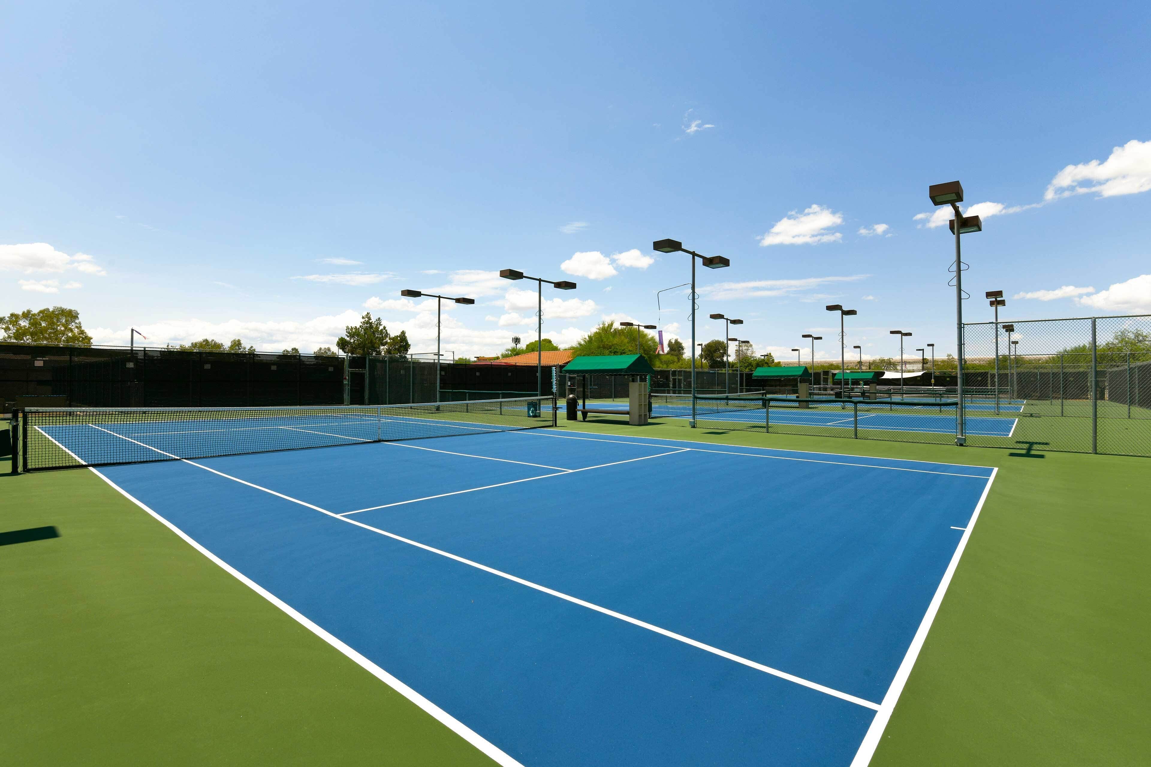 Pistas de tenis con superficies verdes y azules, y vallas aledañas.