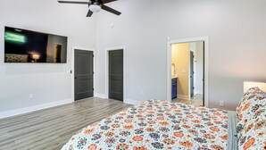 Un dormitorio con cama, ventilador de techo y puerta que da a otra habitación.