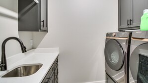 Una cocina compacta con un lavamanos de acero inoxidable, horno empotrado y lavadora.