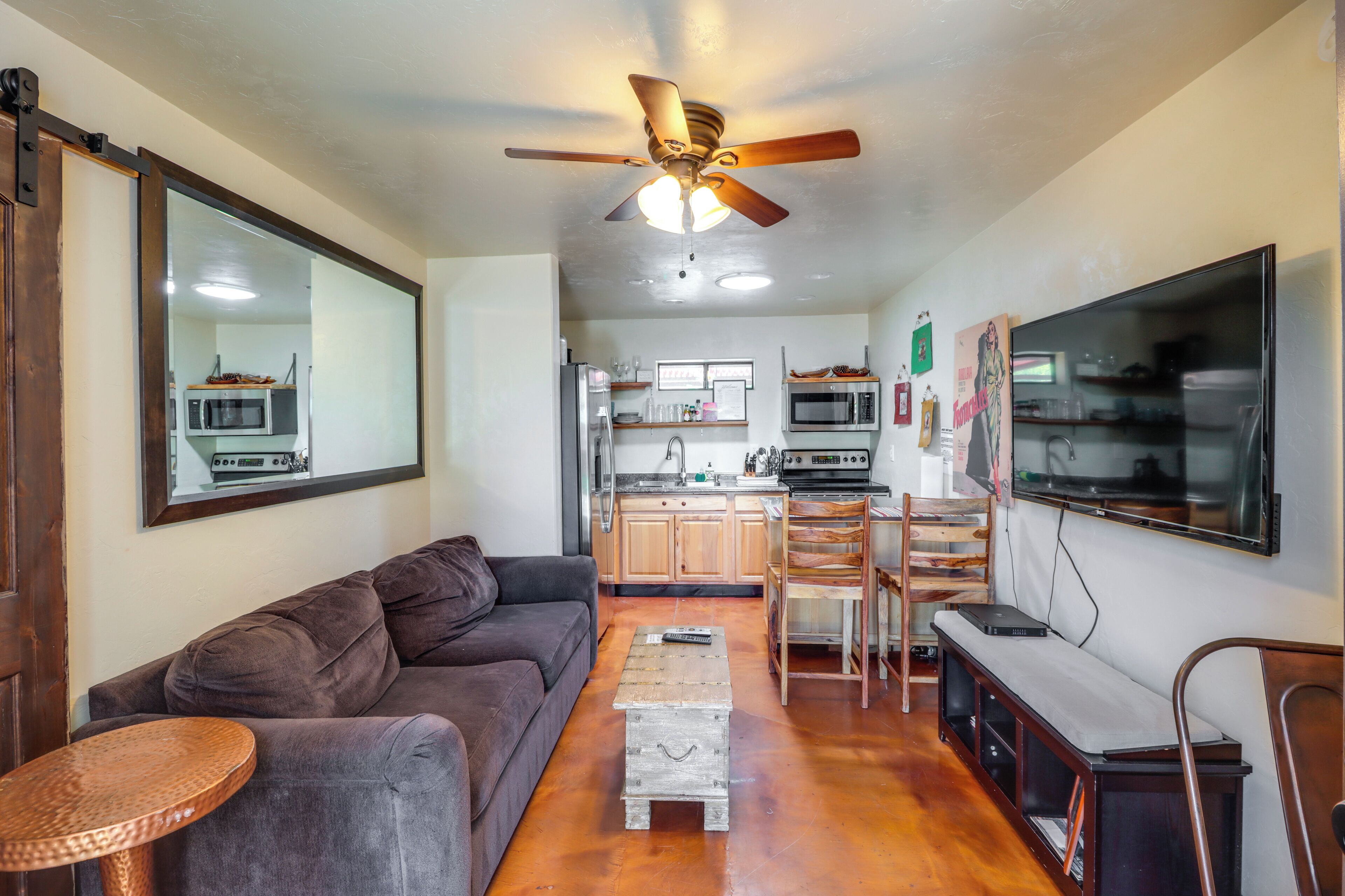 A living room with a sofa, a coffee table, a TV, and a ceiling fan.