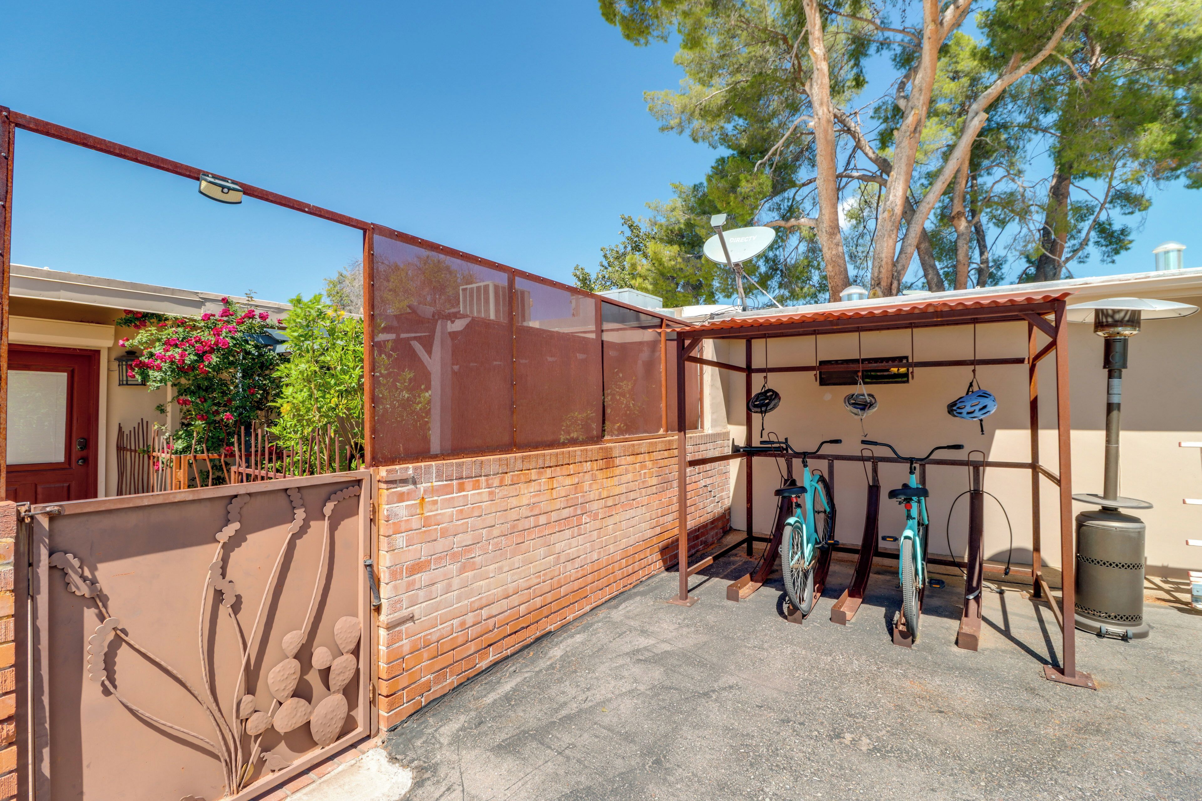 A fenced outdoor area with a bicycle rack, a satellite dish, and a trash can.