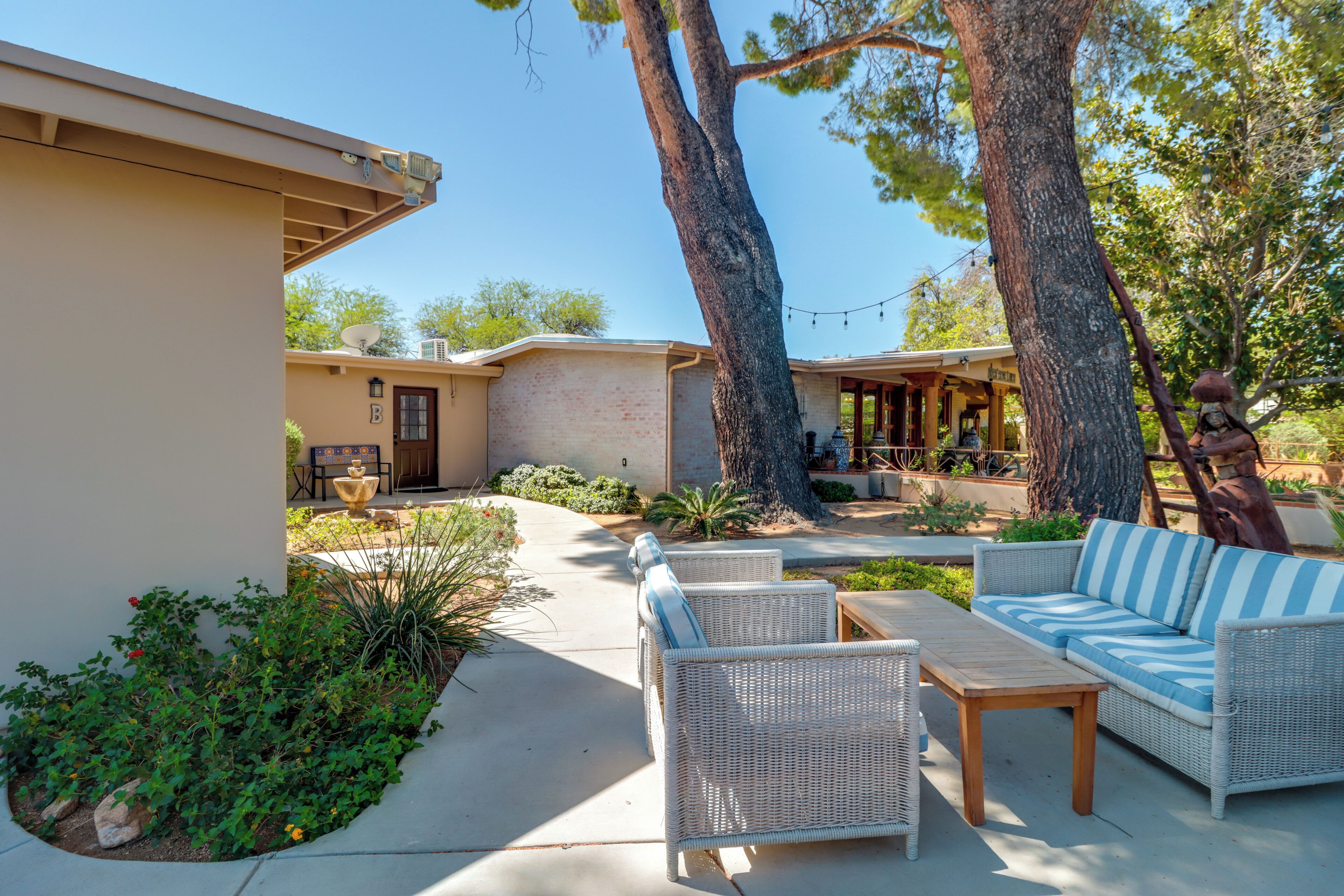 A patio area with wicker furniture, a small table, and a building with a door and windows.