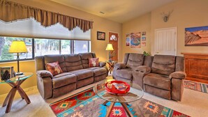 A living room with two brown sofas, a glass coffee table, a red tray, a patterned rug, and a window with blinds. - Arizona Home w/ Patio, Fire Pit & Gas Grill (Williams)