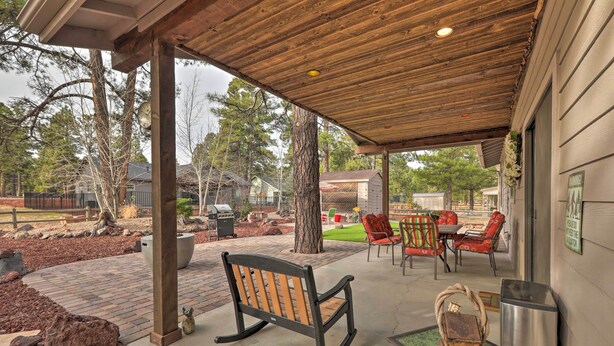 A covered patio area with a wooden bench, outdoor furniture, and a trash can. - Arizona Home w/ Patio, Fire Pit & Gas Grill (Williams)