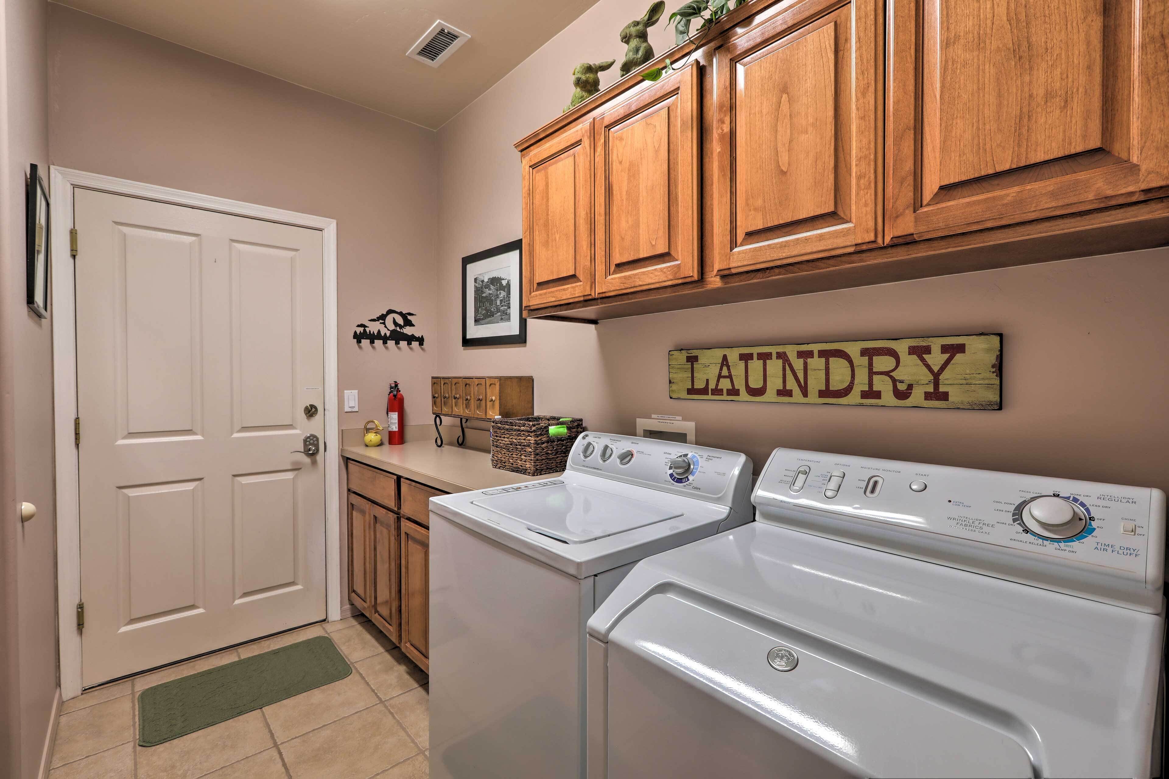 A laundry room with wooden cabinets, a white door, and a wall-mounted sign that reads "LAUNDRY".