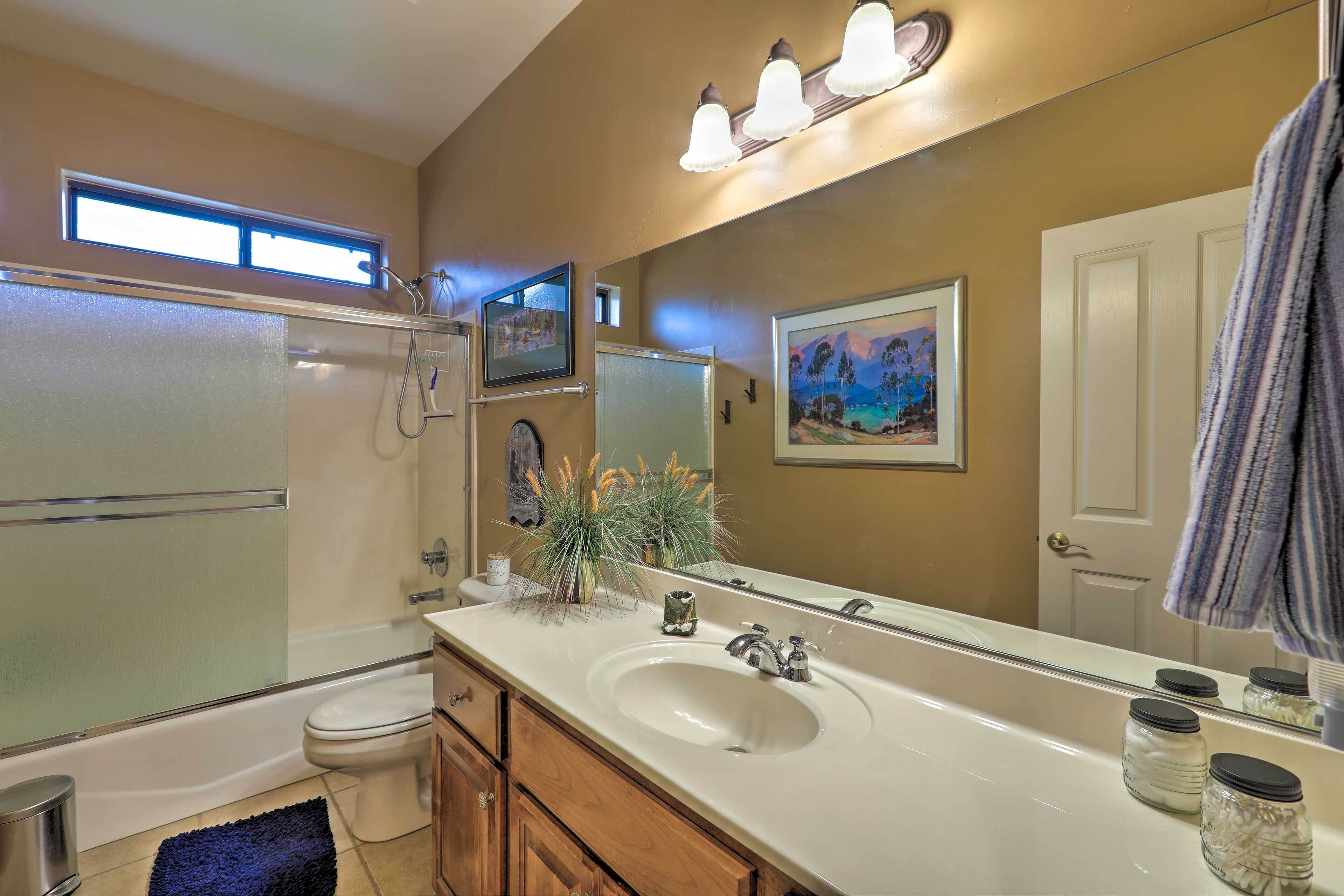A bathroom with a bathtub, toilet, sink, and a large mirror.