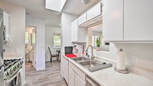 A modern kitchen with white cabinetry, stainless steel appliances, and a granite countertop. - Quaint Sedona Cottage w/ Backyard + Views! (Sedona)