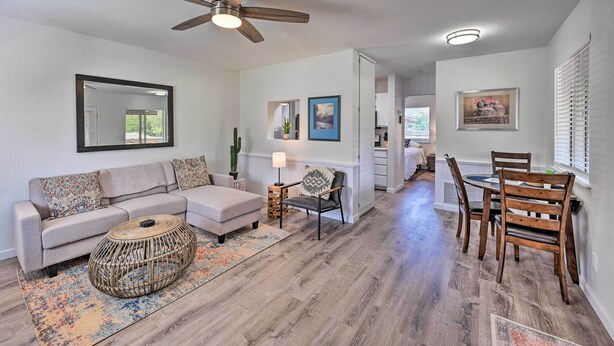 A living room with a sofa, coffee table, and dining table with chairs. There is a ceiling fan, a lamp, and a cactus on a side table. - Quaint Sedona Cottage w/ Backyard + Views! (Sedona)