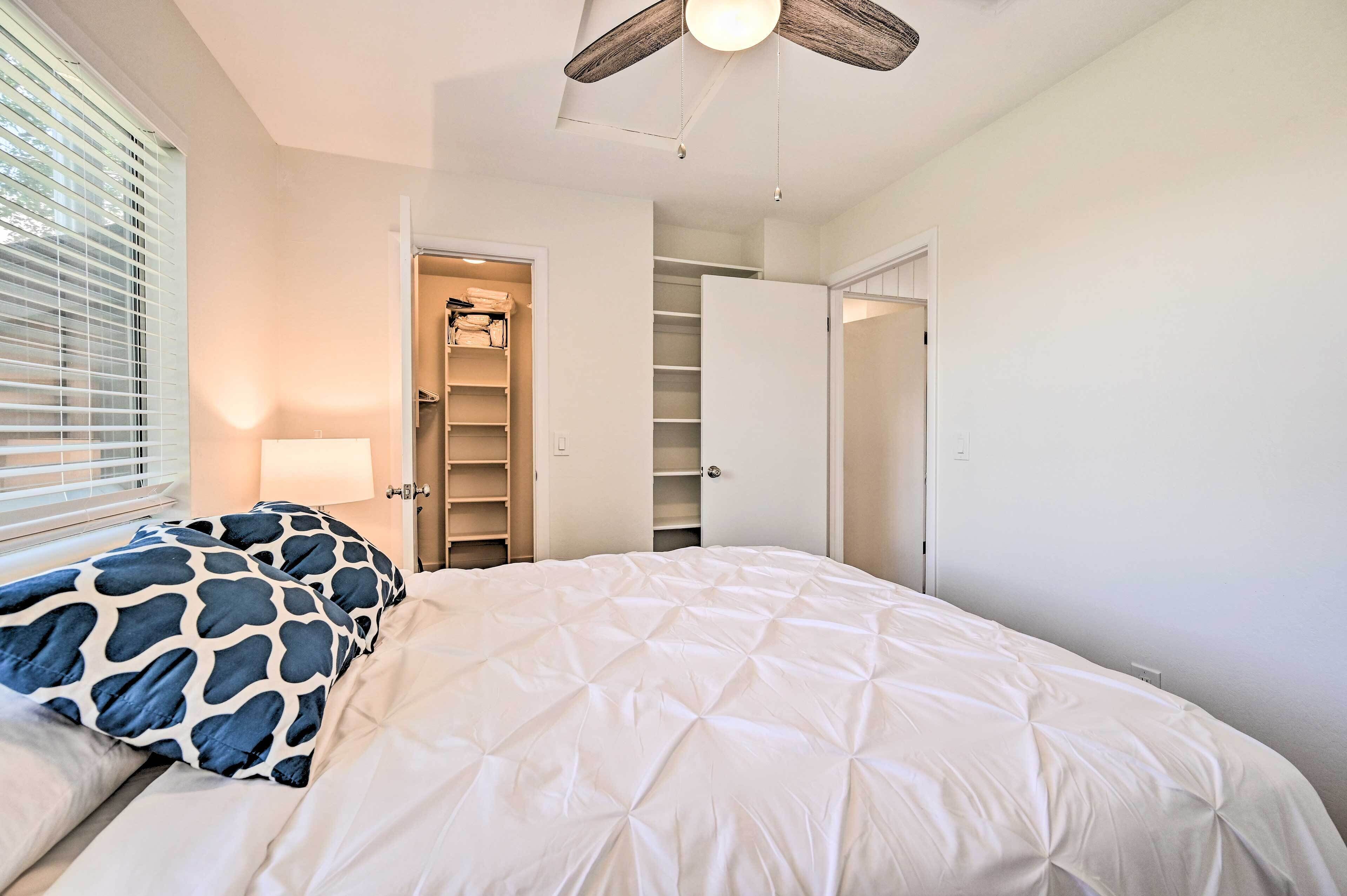 A bedroom with a bed, a ceiling fan, a closet, and a window with blinds.