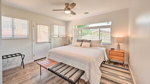 A bedroom with a bed, a bench, a nightstand, a ceiling fan, and a window with blinds. - Quaint Sedona Cottage w/ Backyard + Views! (Sedona)