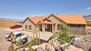 Une maison à deux étages avec une façade en pierre, un toit rouge et un petit garage attenant.