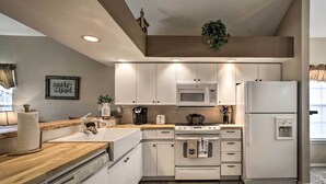 Une cuisine moderne avec des meubles blancs, un four à micro-ondes, un réfrigérateur et un plan de travail en bois.