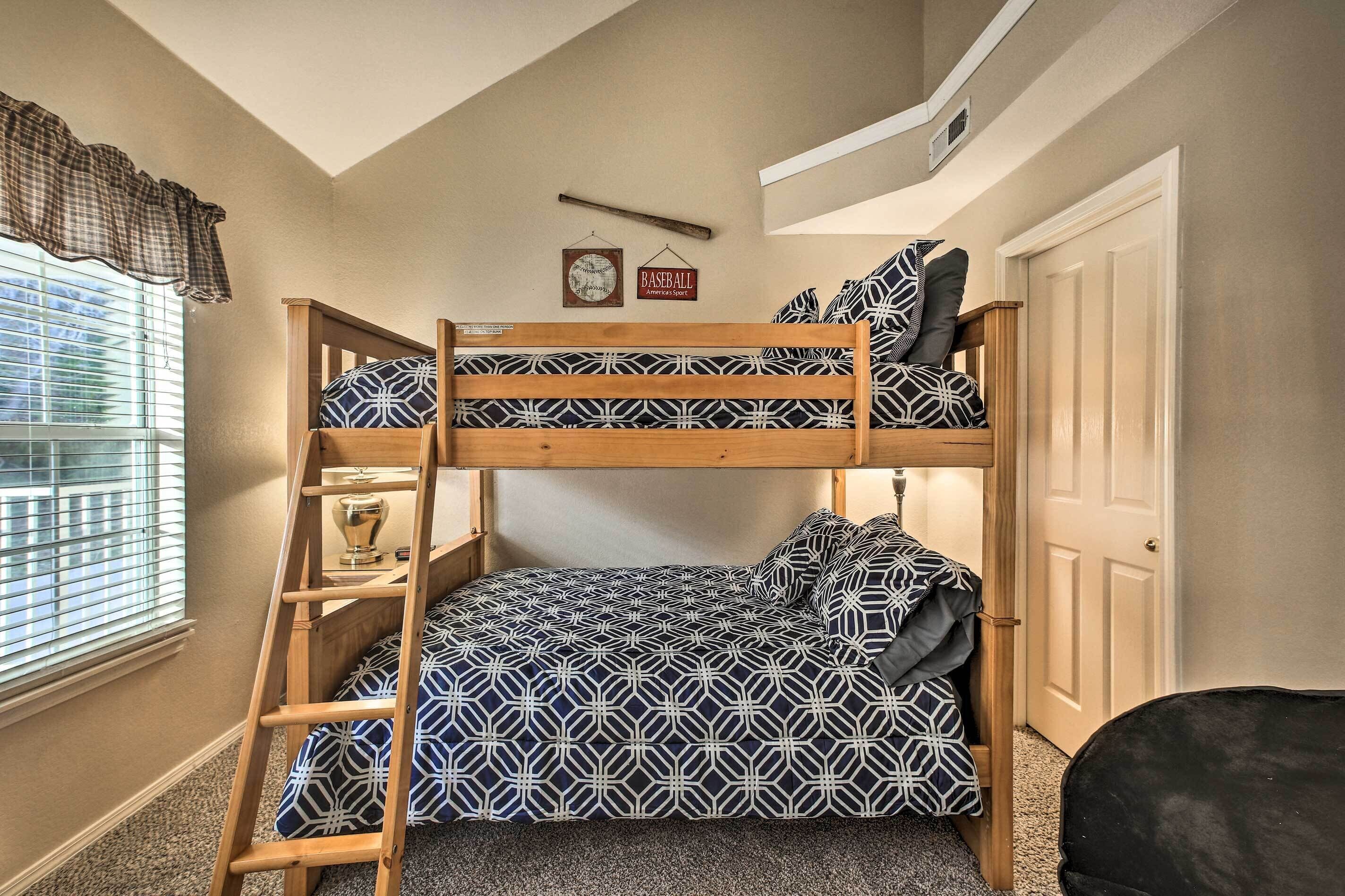 A bunk bed with a geometric patterned bedspread, a ladder, and a baseball-themed wall decoration.
