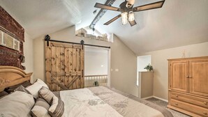 Une chambre à coucher avec un lit, une armoire en bois, un ventilateur de plafond et un mur au style rustique.