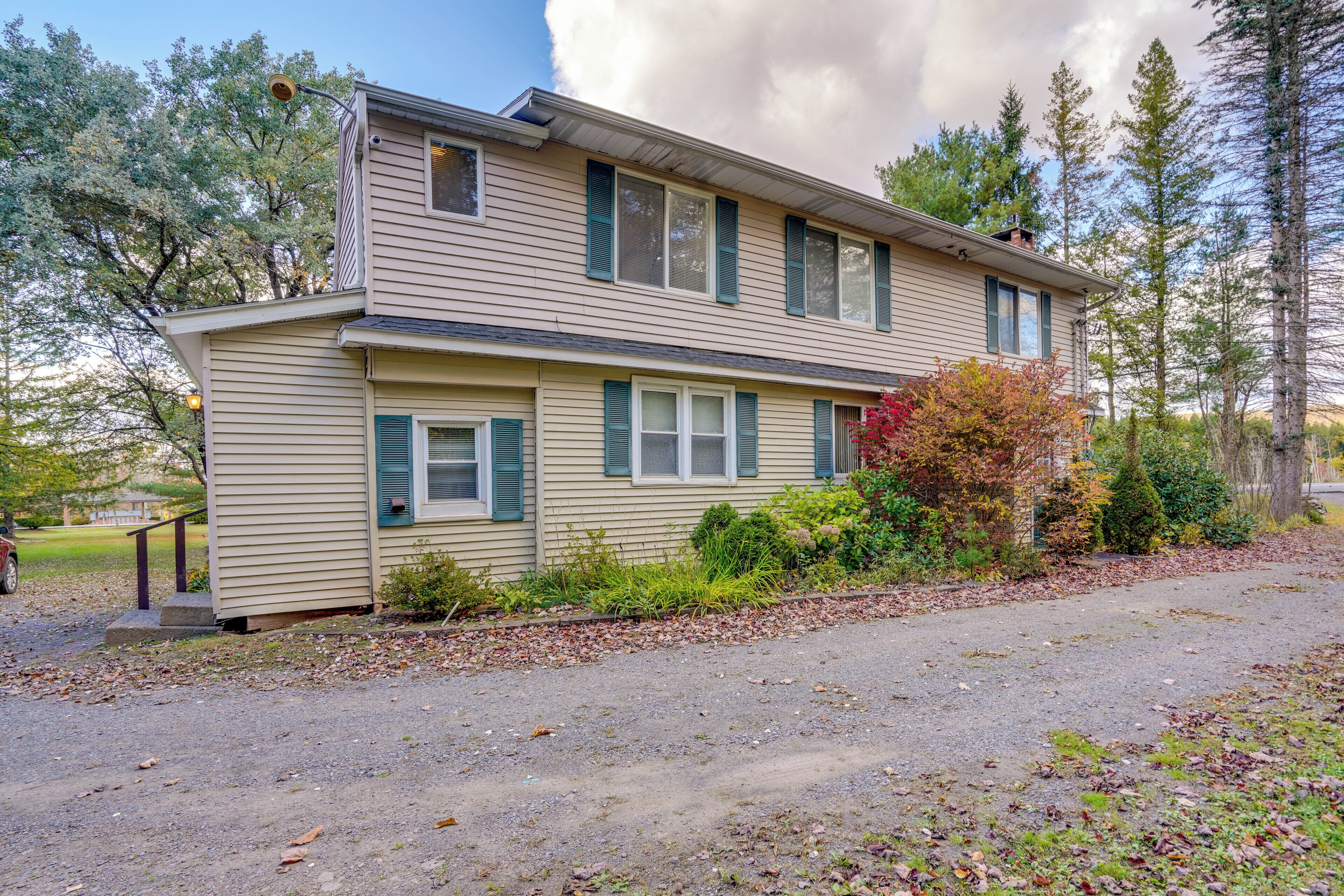 A two-story building with a gravel driveway and a small porch.