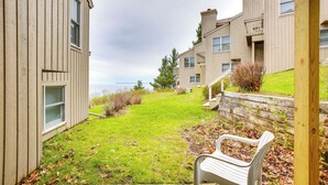 A view of a residential building with a grassy yard and a wooden bench. - Glen Arbor Vacation Rental w/ Views of Lake! (Glen Arbor)