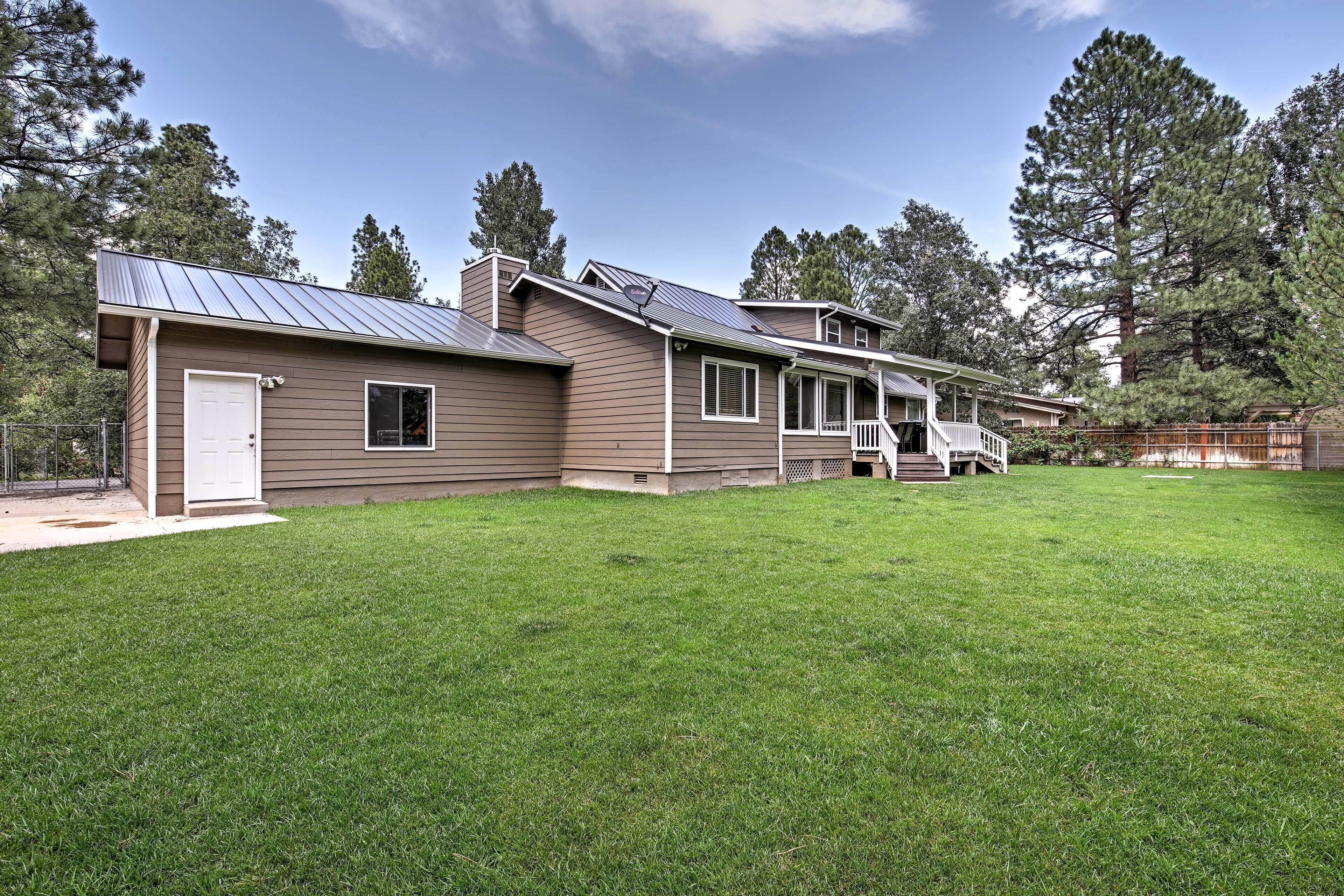A two-story house with a covered porch, a fenced yard, and a metal roof.