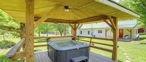 Een houten terras met een jacuzzi en een overdekte zithoek.