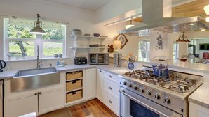 A modern kitchen with white cabinetry, a stainless steel sink, a built-in oven, and a gas stove.