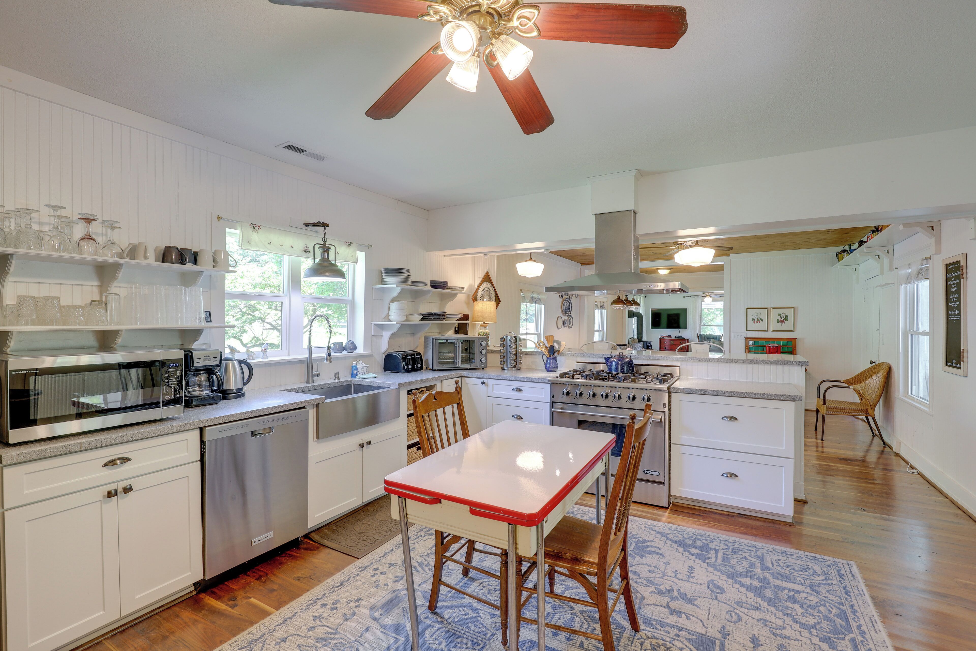 A spacious kitchen with white cabinetry, a central island, and a ceiling fan.