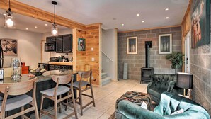 Una cucina moderna con elementi in legno, un'area pranzo con sgabelli da bar, un camino e un'accogliente zona salotto con un divano confortevole.