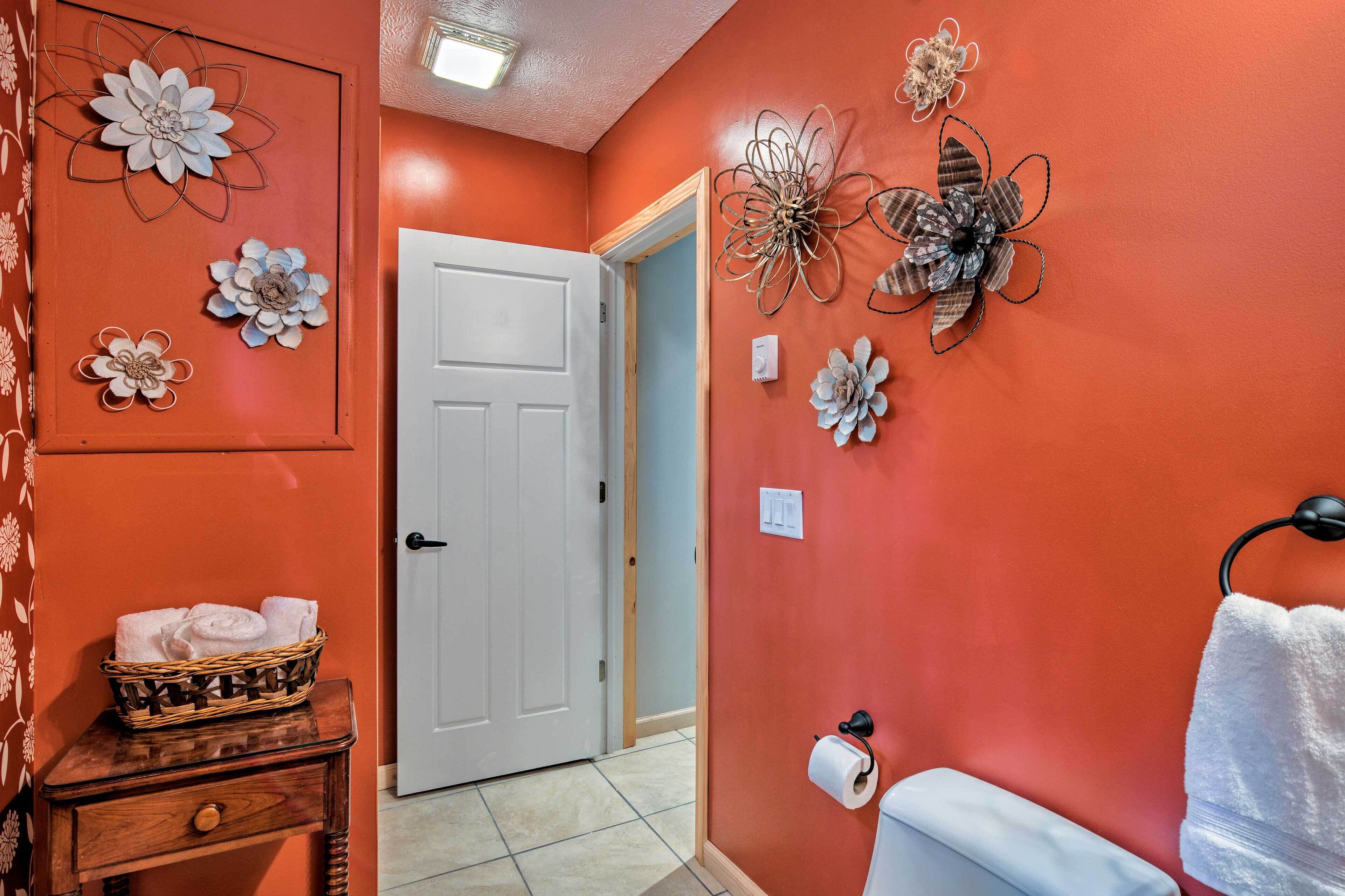 A bathroom with a red wall, a white door, and a towel rack with a white towel.