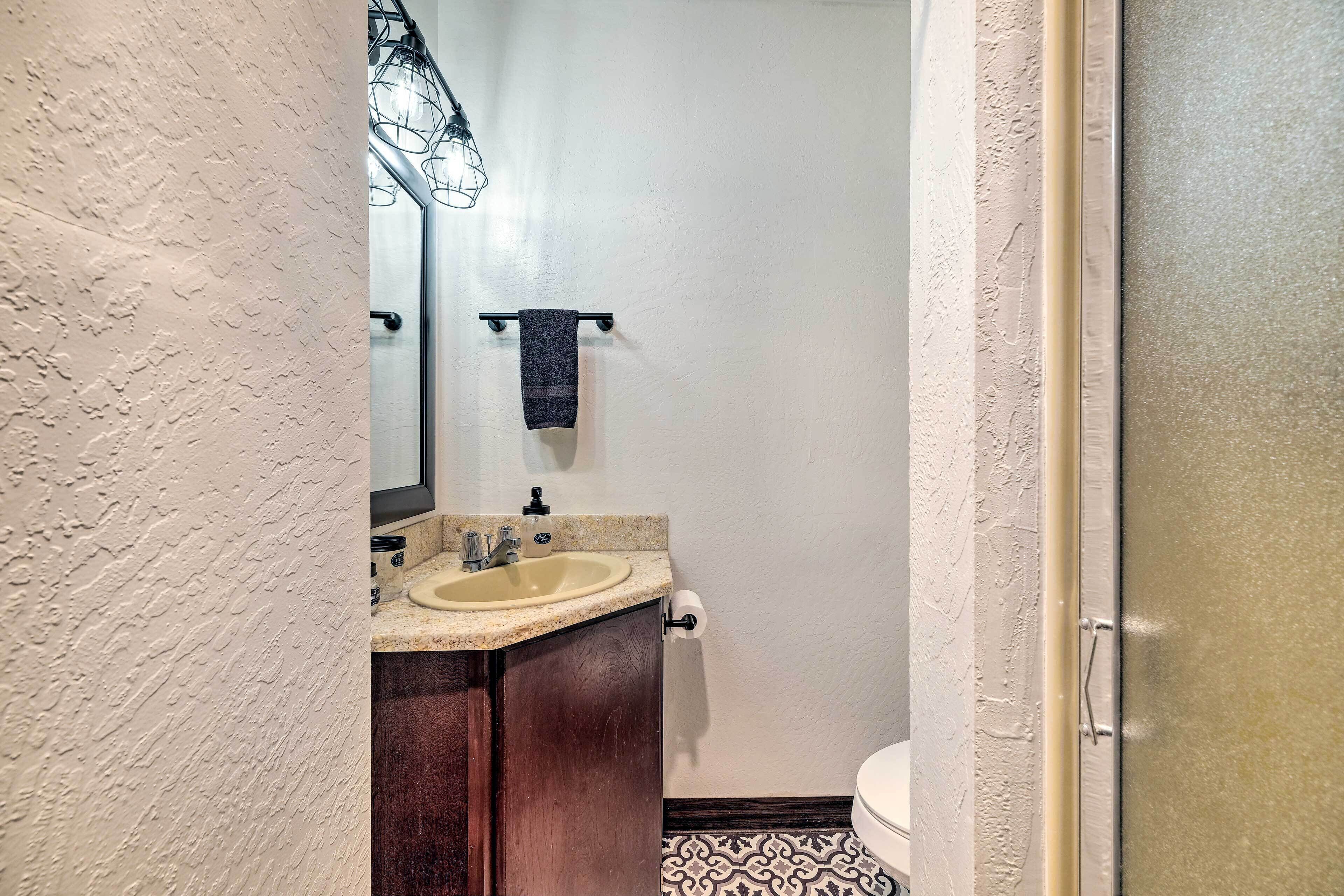 A bathroom with a beige sink, dark wooden cabinet, white walls, and a patterned floor.