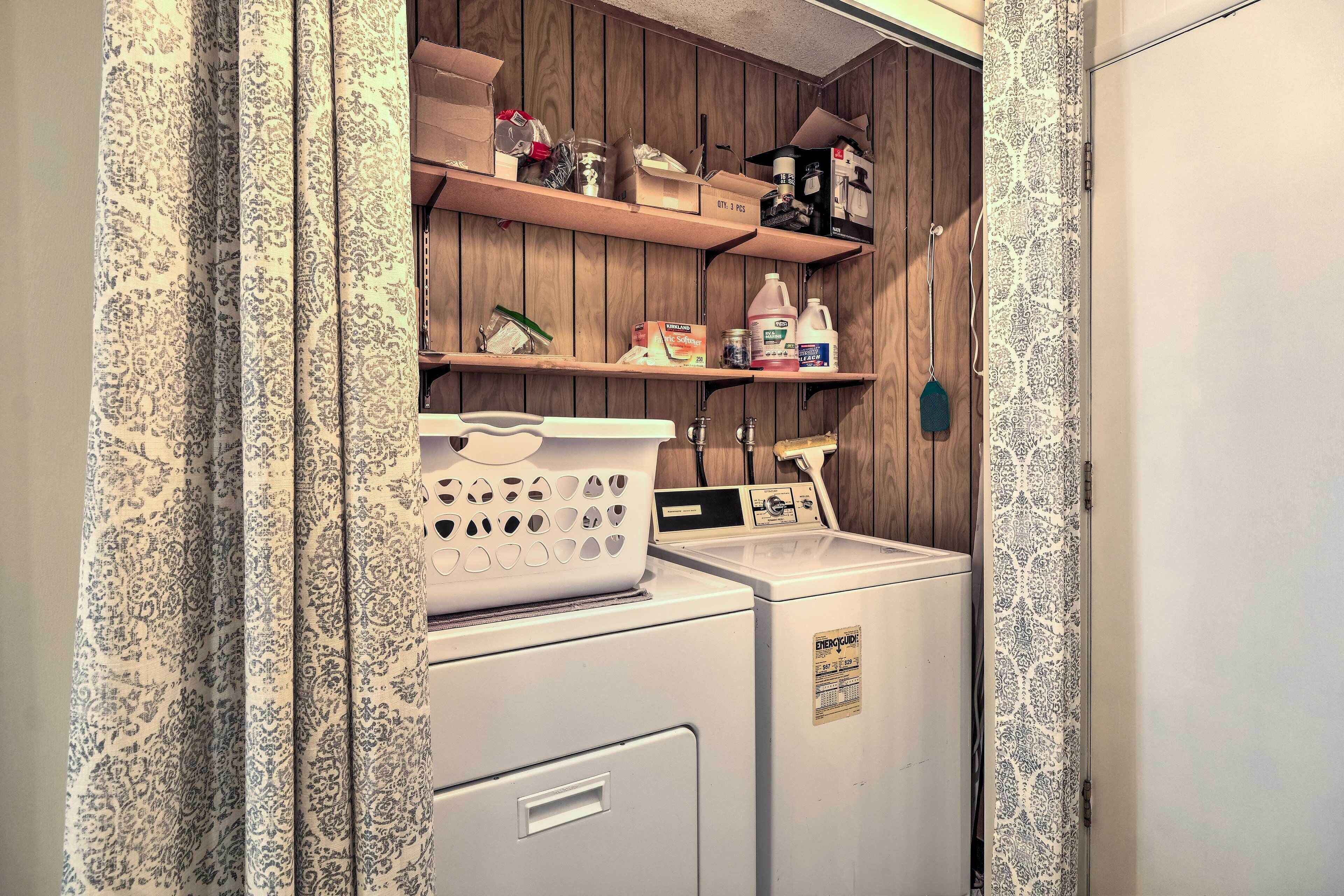 A laundry area with a washing machine, dryer, and shelves with various items.
