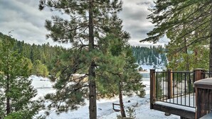A snowy forest with a wooden deck and a bench.