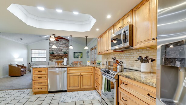 A modern kitchen with wooden cabinets, stainless steel appliances, and a central island. - Valrico Vacation Rental 15 Mi to Tampa (Valrico)