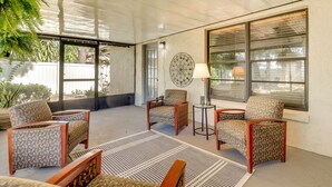 A covered outdoor seating area with patterned chairs and a table, large windows, and a decorative wall piece. - Valrico Vacation Rental 15 Mi to Tampa (Valrico)