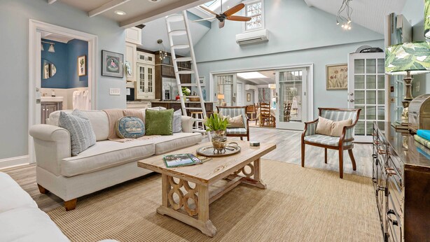A spacious living room with a high ceiling, a ceiling fan, and a large window. - Guilford Carriage House at Granite Lodge! (Guilford)