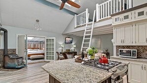 A spacious kitchen with a large island, a dining area, and a bedroom with a balcony. - Guilford Carriage House at Granite Lodge! (Guilford)