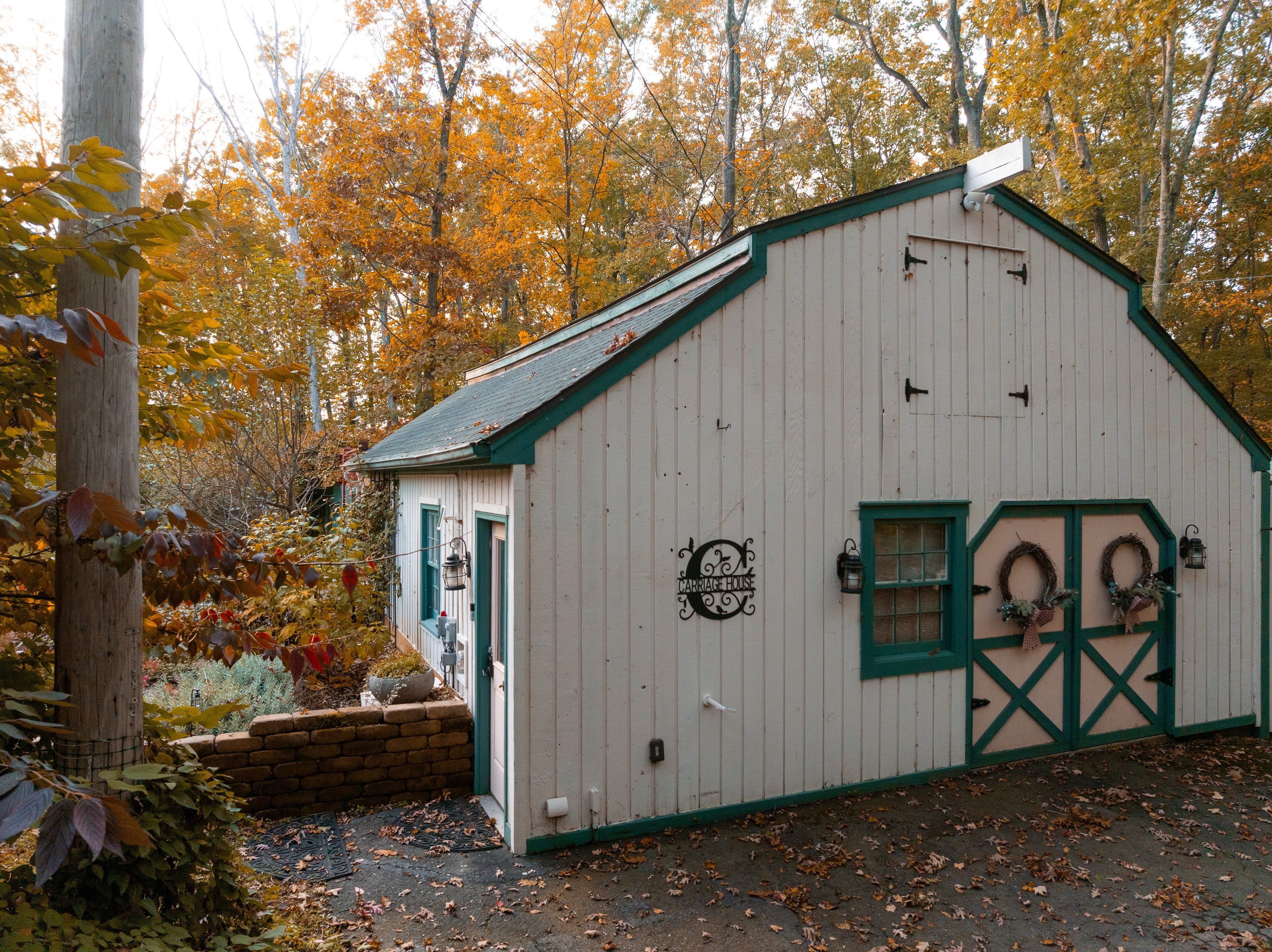 A white building with green trim and a sign that reads 'CARRIAGE HOUSE.'