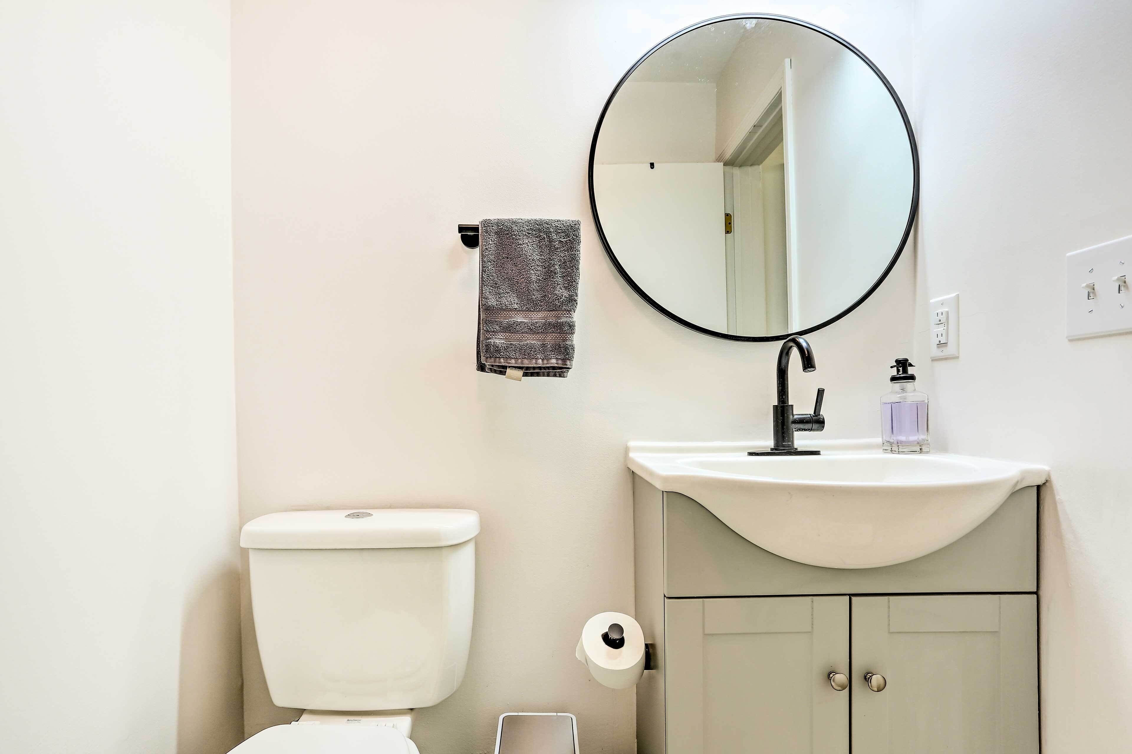 Ein Badezimmer mit Toilette, Waschbecken, Spiegel, Handtuch und Toilettenpapier.