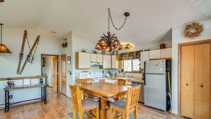 A spacious kitchen with wooden flooring, a central island, and a chandelier.