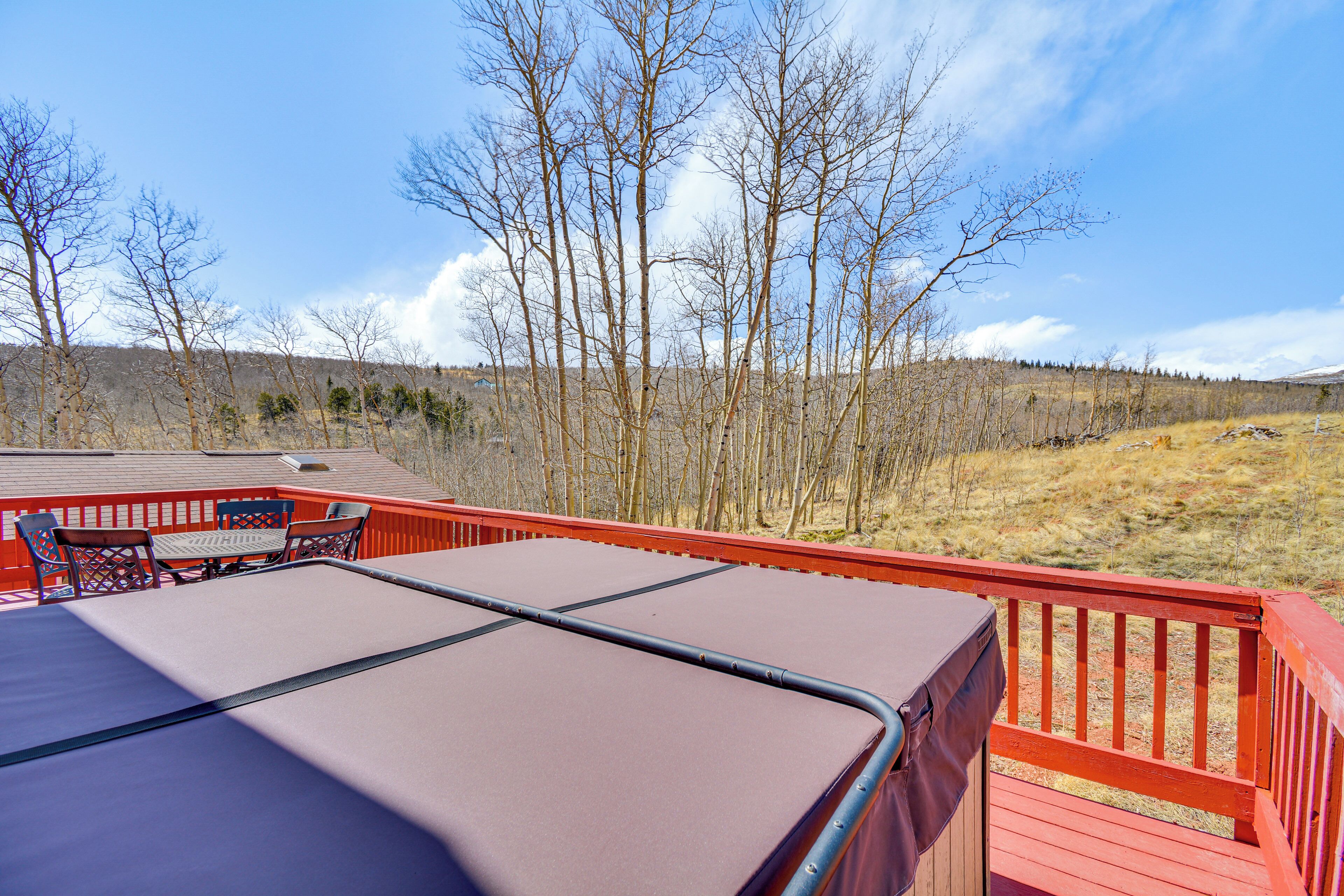 A deck with a table and chairs, overlooking a forested area.