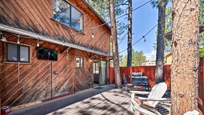 Une cabane en bois dotée d’une terrasse, d’un espace salon extérieur et d’un coin barbecue.