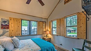 Une chambre à coucher avec un lit, une chaise et de grandes fenêtres dotées de volets en bois.