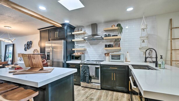 Una cocina moderna con una isla central, electrodomésticos de acero inoxidable y un salpicadero blanco.